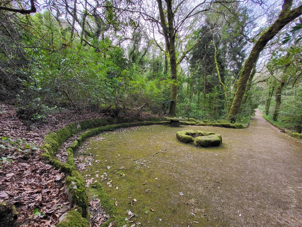 A semi-circle bench surrounds a stone fireplace in the Pena Palace Park in Sintra, Portugal.