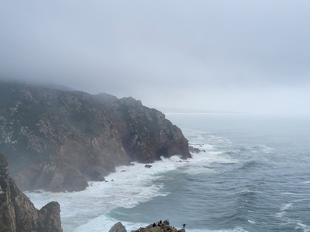 The rocky cliffs of Cabo da Roca rise above the rolling and crashing waves of the Atlantic Ocean.
