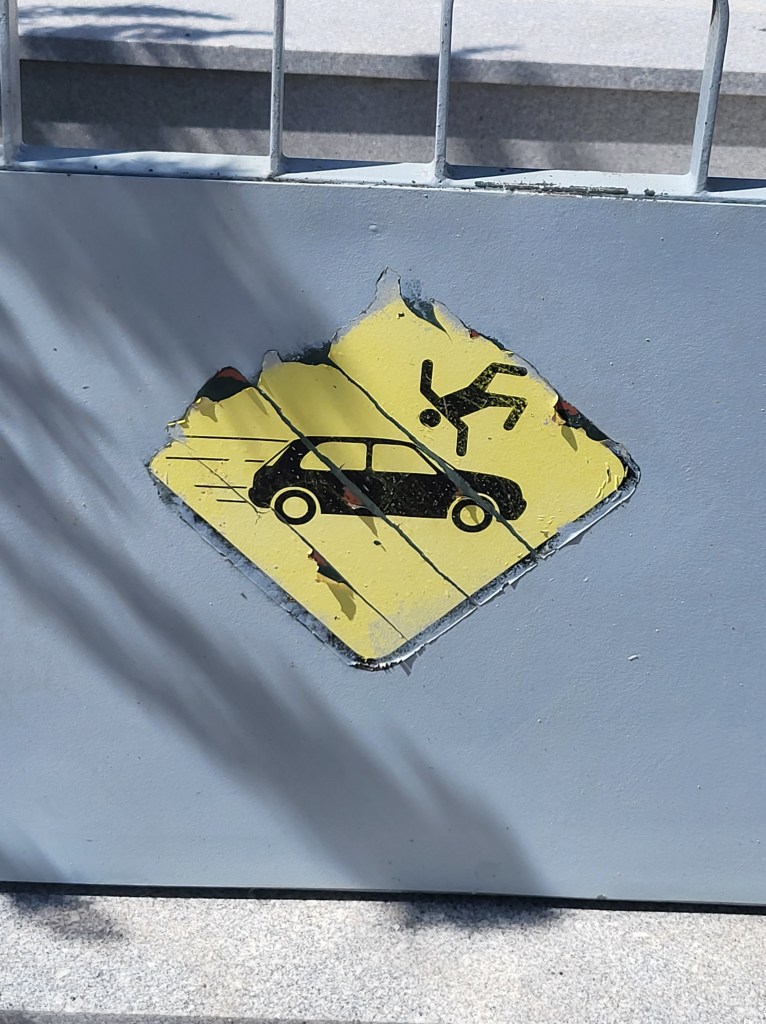 Street Sign with an image of a speeding car and a pedestrian flying through the air.