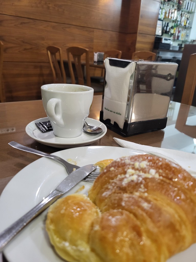A croissant and a cup of coffee on a tabletop in Vigo, Spain.