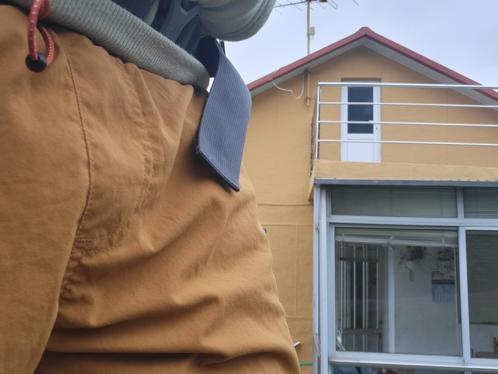 A closeup view of a hiker, a house in the background.