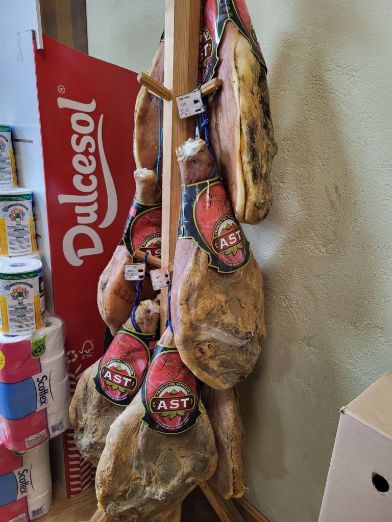 Cured ham hanging in market.