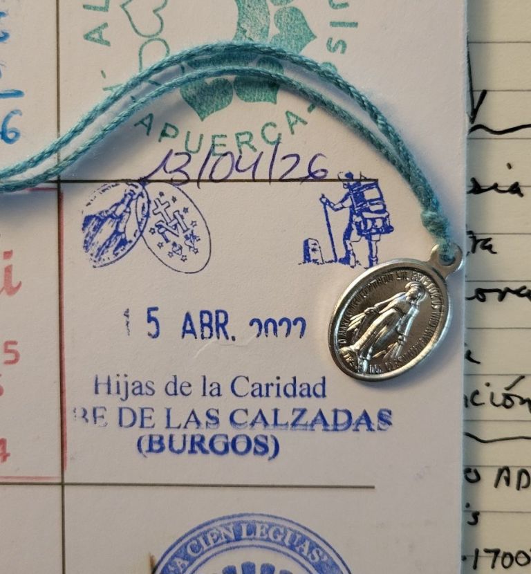 A pilgrim's passport with stamps and a simple necklace.