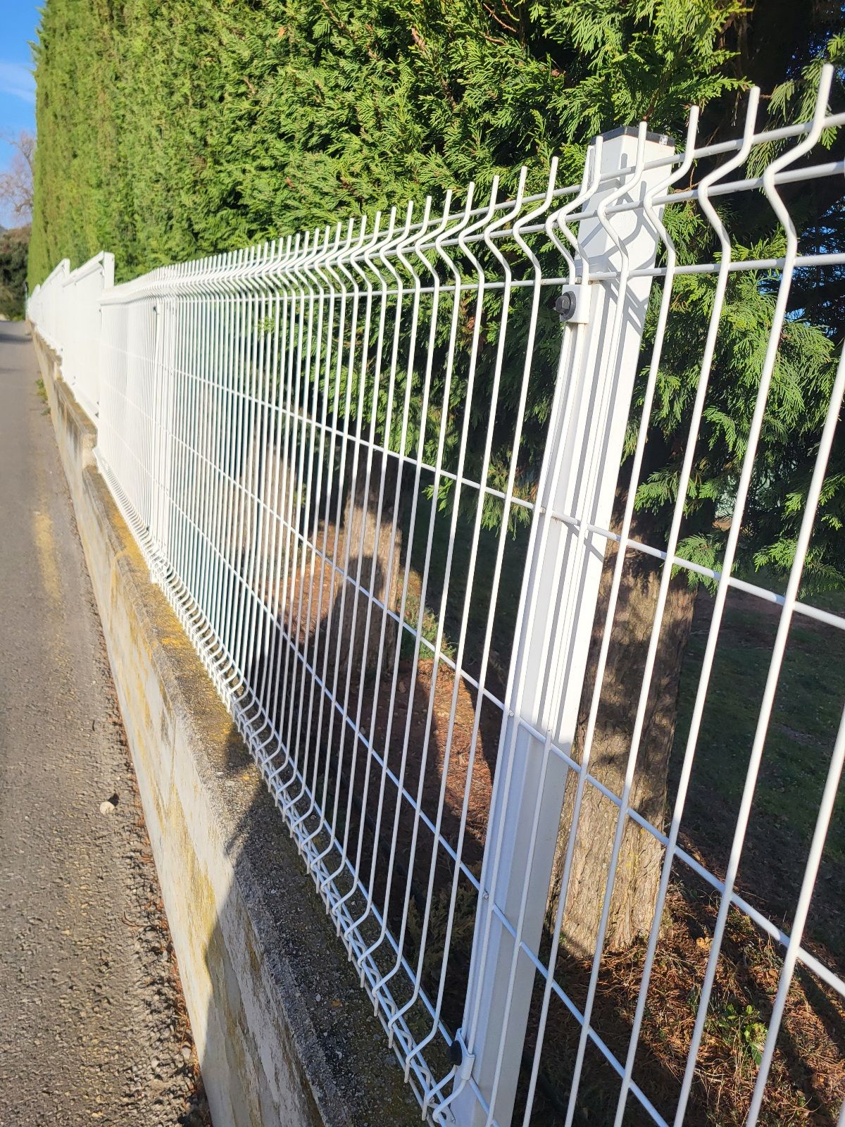 A sidewalk next to a fenceline.