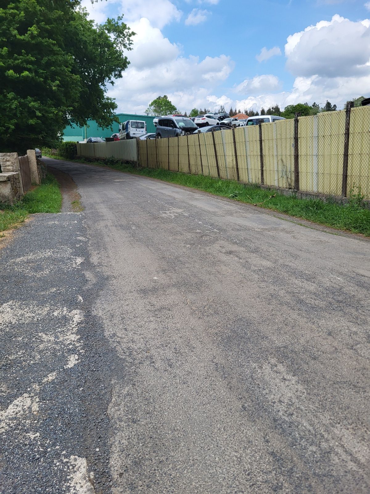 A street next to an auto junkyard.